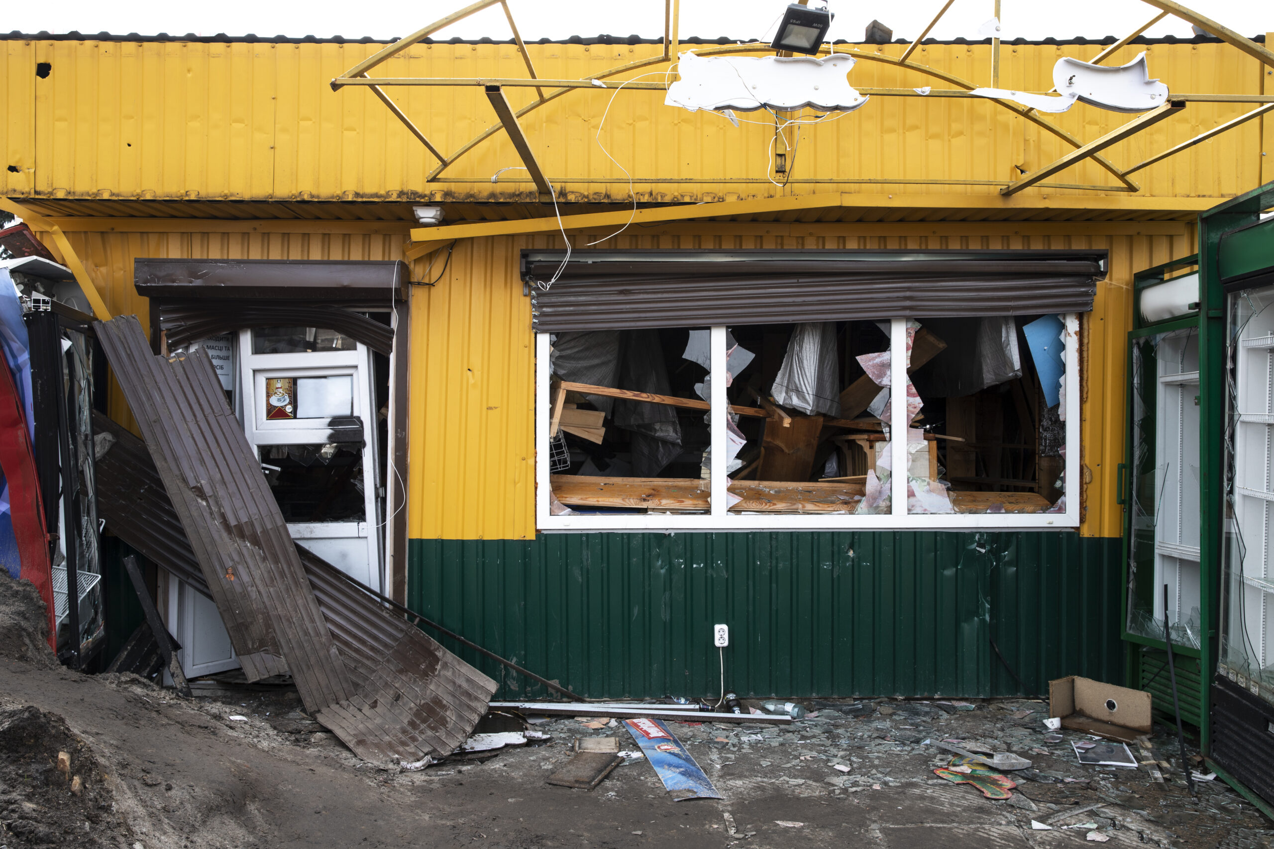 Damaged yellow building with a broken window and debris