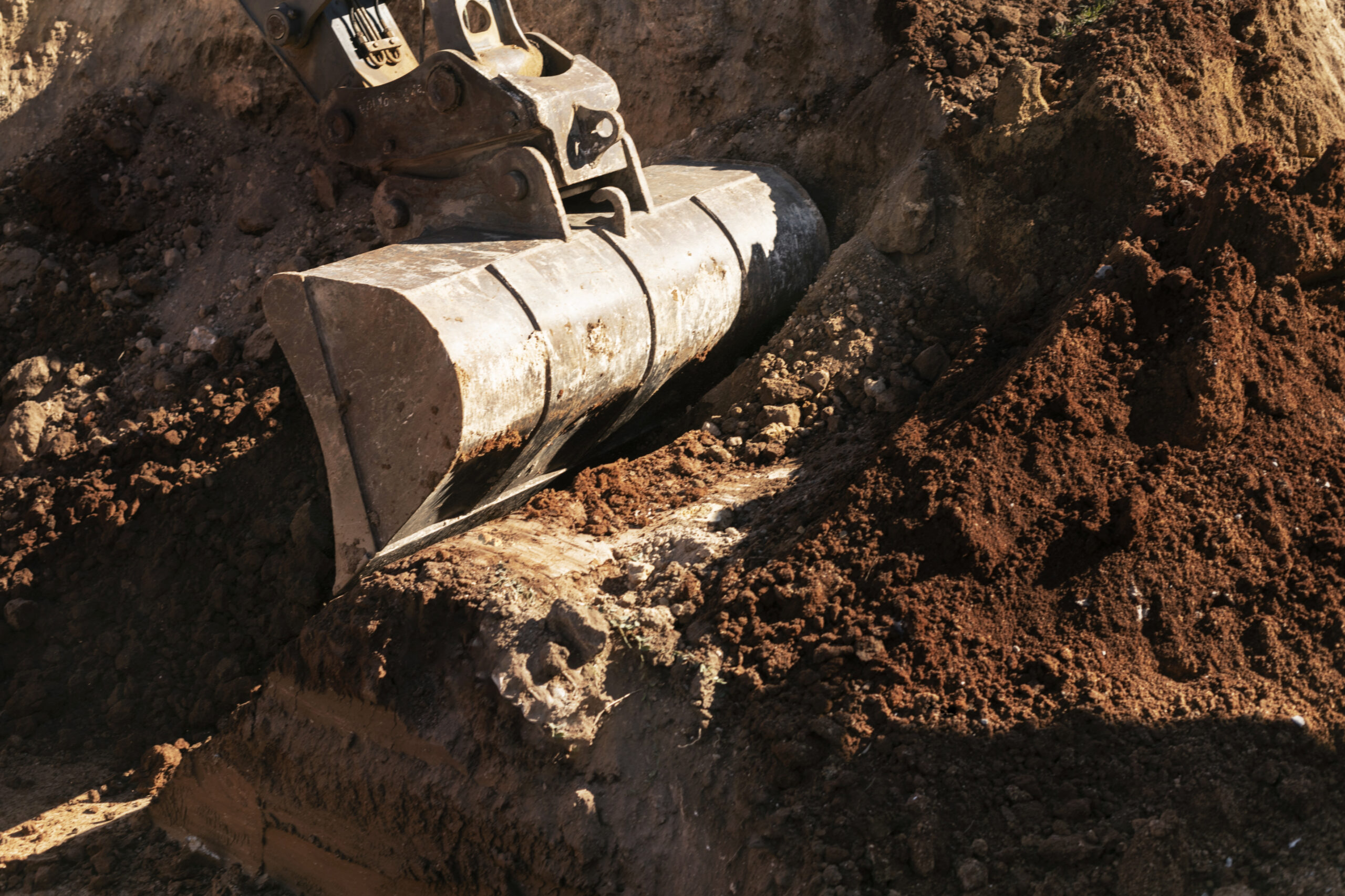Close-up of an excavator bucket digging into soil